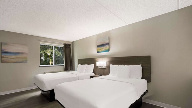 Ein Hotelzimmer mit zwei Betten, einem großen Fenster und Bildern an den Wänden.