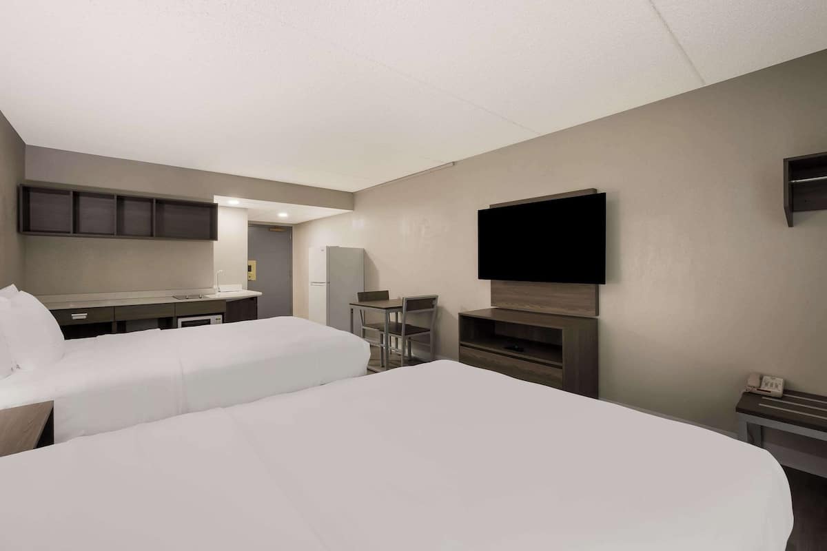 Ett hotellrum med två sängar, ett skrivbord, en stol, en TV och en minibar.
