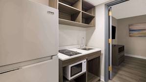 Eine moderne Küche mit integriertem Mikrowellenherd, Spüle und Herd. Darüber befinden sich Holzregale und darunter ein Schrank.