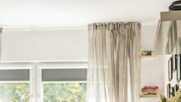 A dining area with a glass table set for four, a sofa in the background, and a window with curtains. - Cozy Apartment in a quiet area | Washing machine | Close to the Park (Poznan)