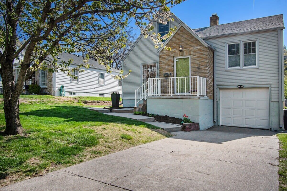 A two-story house with a front porch, a garage, and a well-maintained lawn.