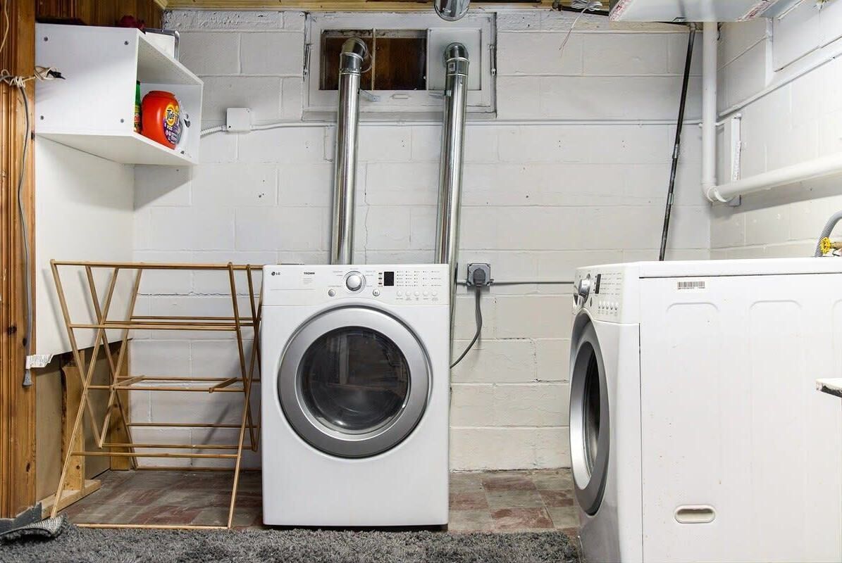 A laundry room with a washing machine, dryer, and a shelf with a can.