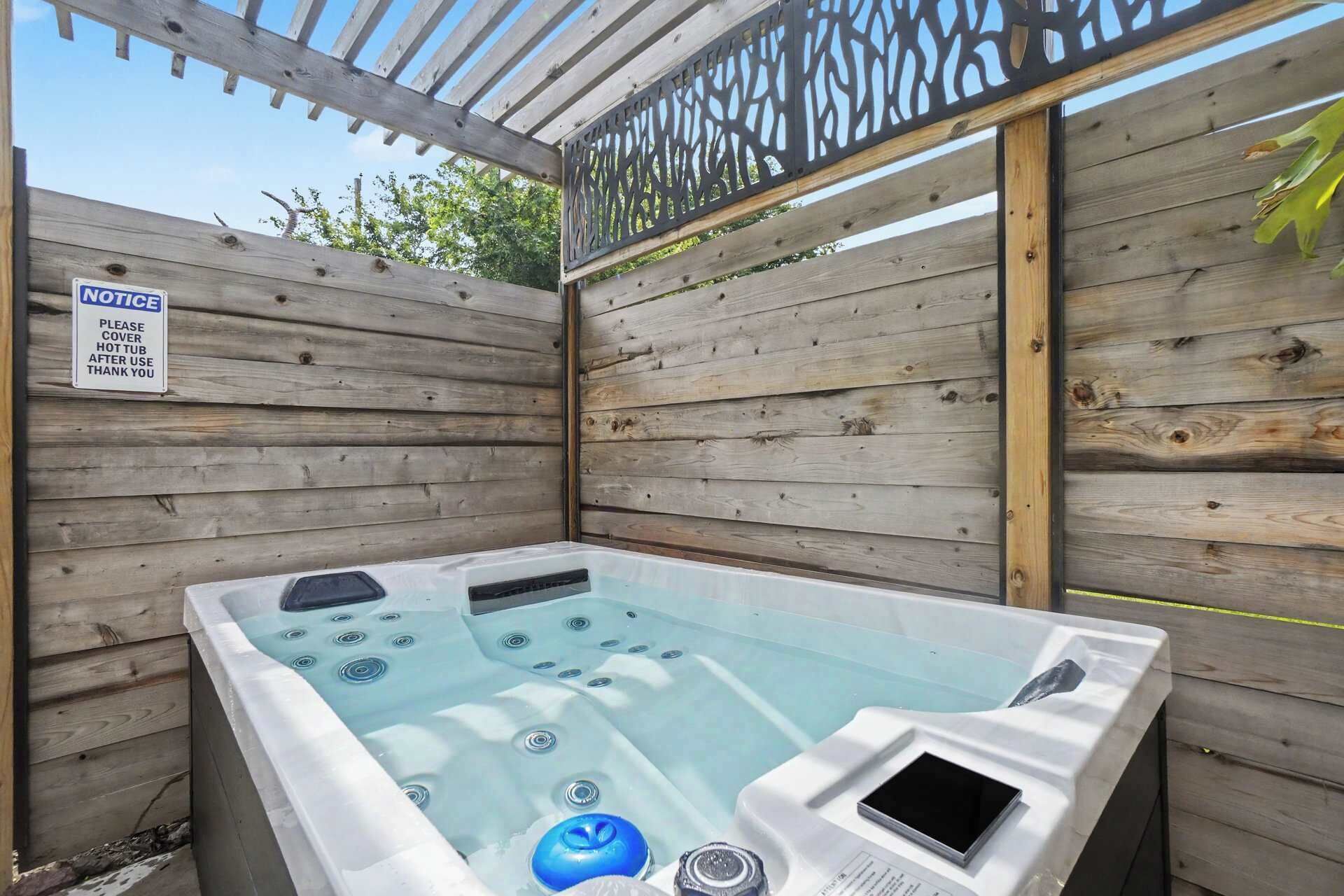 A hot tub with a wooden deck and a sign requesting to cover it after use.
