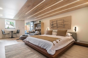A modern bedroom with a large bed, a desk, and a chair. - Luxury Studio King Suite, Hot tub, minutes to UNMC! (Omaha)
