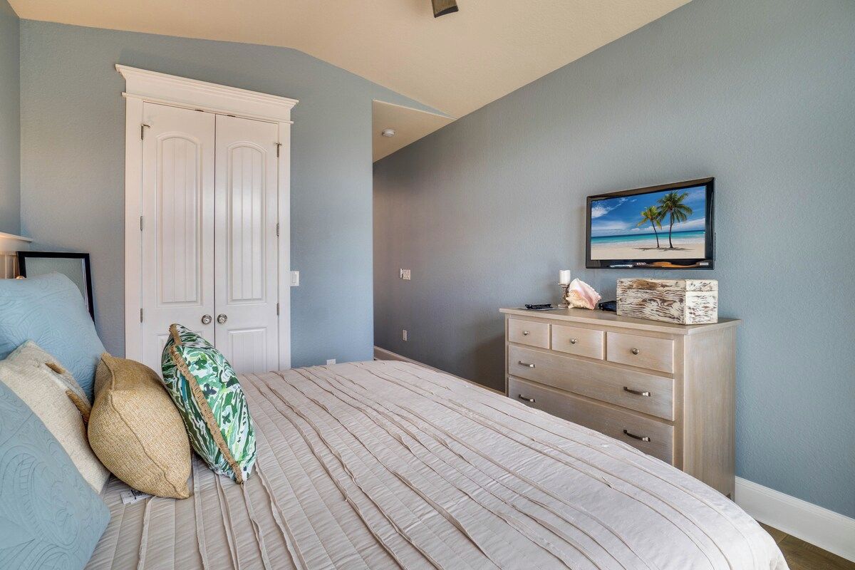 A bedroom with a bed, a dresser, a television, and a door.