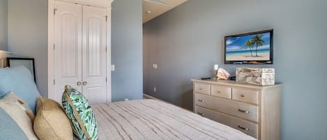 A bedroom with a bed, a dresser, a television, and a door.