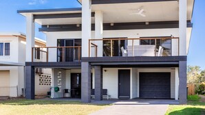 A modern two-story house with a flat roof, large windows, and a balcony. - Beautifully Renovated Large Home on Lammermoor Beach. (Yeppoon)
