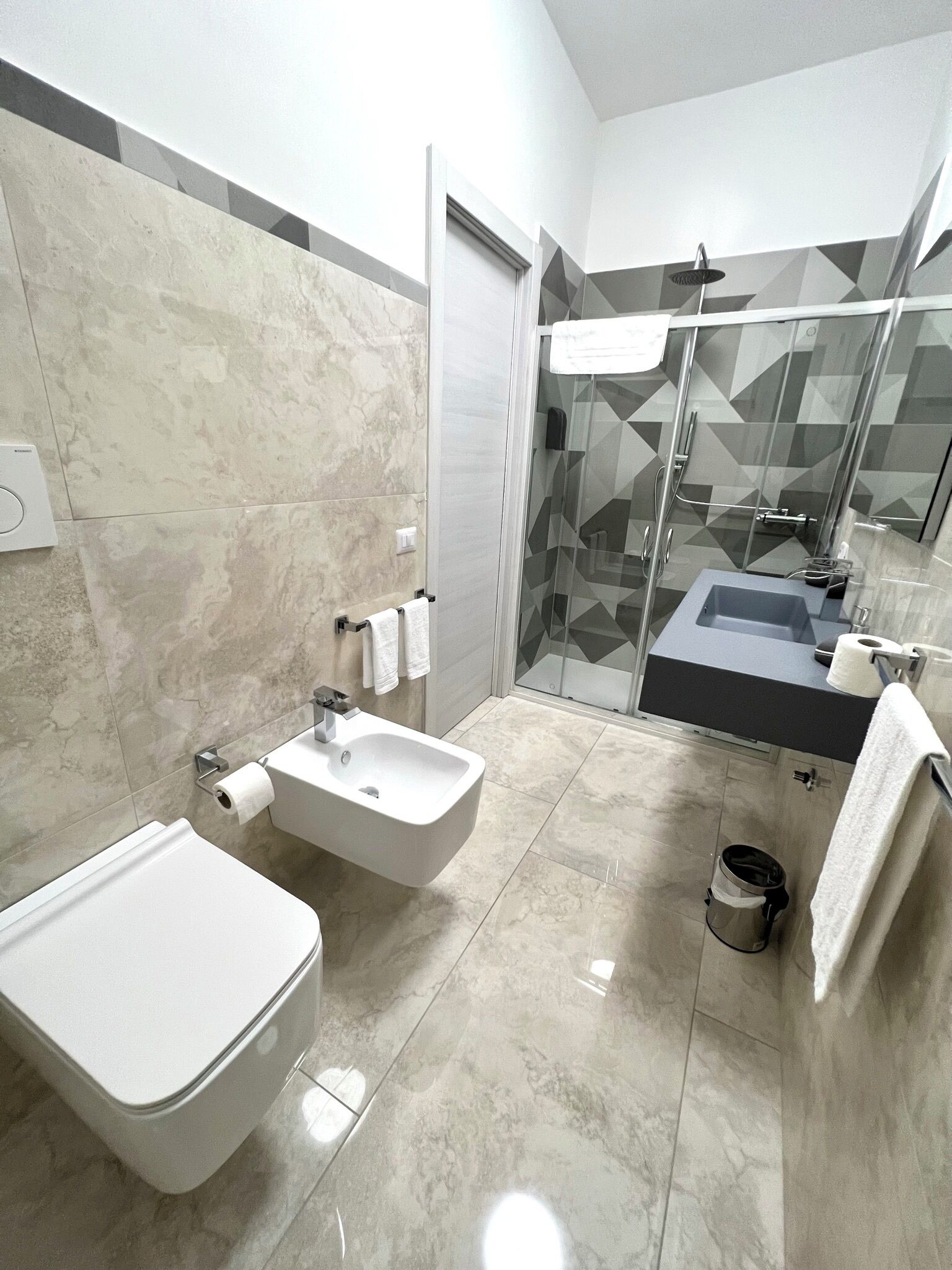 A modern bathroom with a bidet, sink, and glass shower enclosure.
