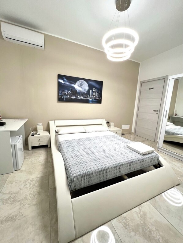 A modern bedroom with a bed, bedside tables, a desk, and a large mirror. - Circeo Boutique Rooms  (San Felice Circeo)