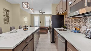 Una cocina moderna con una isla central, electrodomésticos de acero inoxidable e iluminación decorativa.