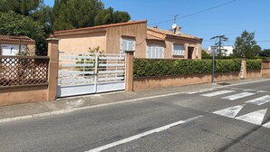 A residential property with a gated entrance, a tiled roof, and a paved road with pedestrian crossing. - Villa Avec Terrasse et Jardin (st mitre les remparts)