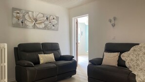 A living room with two dark brown leather sofas, a large floral painting on the wall, and a white radiator. - Villa Avec Terrasse et Jardin (st mitre les remparts)