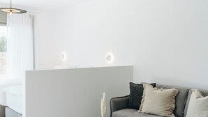 A modern living room with a grey sofa, a round coffee table, and a hanging woven light fixture.