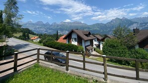 A residential area with houses, a road, and a mountain range in the background. - Cozy 2BR Apartment with Mountainview* Free Parking (Flums)