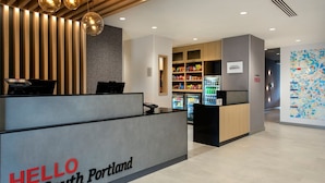 Un espace d'accueil avec une pancarte indiquant « BIENVENUE à South Portland », un comptoir de réception, un bar servant des collations et des boissons fraîches, et un mur orné d'une carte.