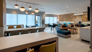 Un hall d’hôtel moderne comprenant un espace repas, des coins salon et un comptoir d’accueil.