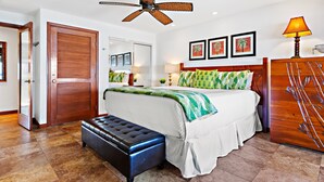 Une chambre à coucher comprenant un lit, un banc, un ventilateur de plafond et une armoire en bois.