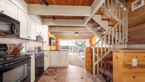 A kitchen with white cabinets, a black stove, and a wooden staircase. - Great oceanfront townhome on 67th Street with multiple decks to enjoy the Atlantic Ocean (Ocean City)