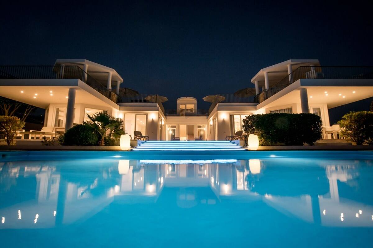 Ett modernt hotell med en stor pool, flera balkonger och en väl upplyst entré.