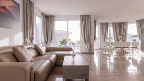 Una sala de estar moderna con un sofá color beige, una mesa de centro y una zona de comedor con sillas y una mesa.