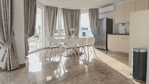 Una cocina moderna con refrigerador, armarios y un comedor con sillas y mesa de vidrio.