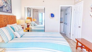 A hotel room with a large bed, a wooden headboard, a bedside table with lamps, and a mirror.
