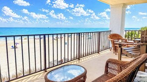 A balcony with wicker furniture, a glass-top table, and a view of the beach and ocean. - Shalimar 2B (North Myrtle Beach)