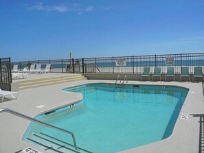 A swimming pool with a lifeguard station, a fenced area, and lounge chairs. - Shalimar 2B (North Myrtle Beach)