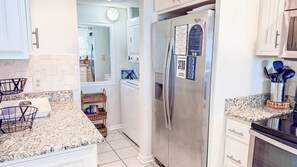 A kitchen with white cabinets, a stainless steel refrigerator, and granite countertops.