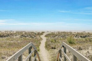 A sandy beach path leading to the ocean with a clear sky. - Turtle Cove | Oceanfront 2BR with Screened Porch Steps from the Dunes (Isle of Palms)