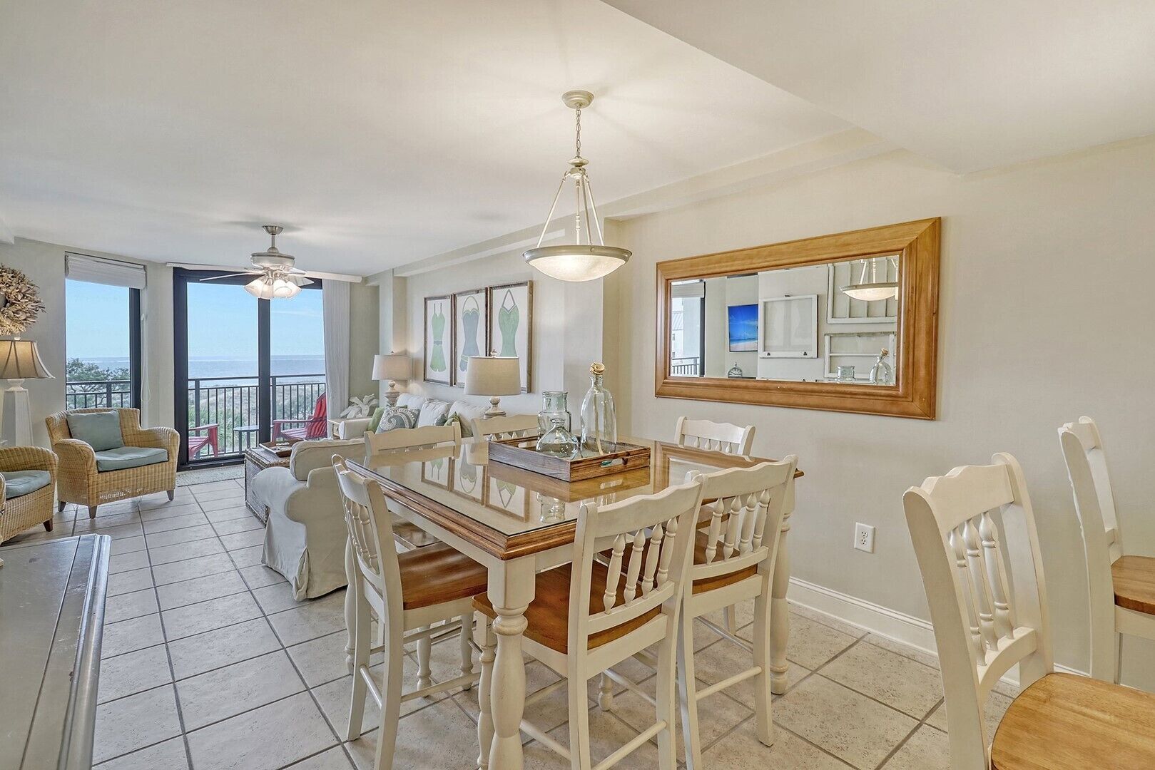 A spacious dining area with a large table and chairs, a ceiling fan, and a view of the outdoors.