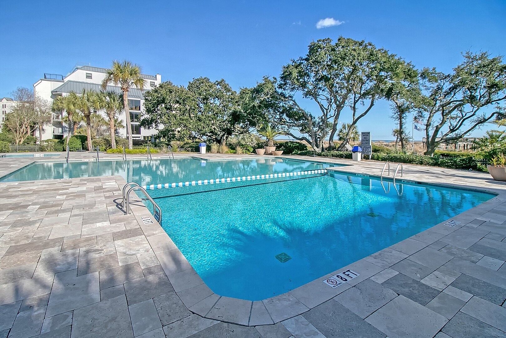 Ein rechteckiger Swimmingpool mit klarem, blauem Wasser, umgeben von einer gefliesten Poolterrasse.