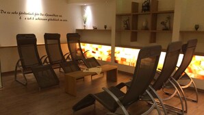 A room with a fireplace, several chairs, a table, and shelves with decorative items.