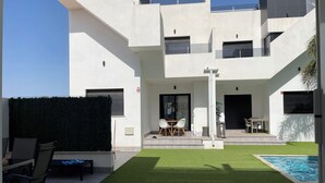 Un edifici modern amb piscina, mobiliari exterior i un jardí ben cuidat.