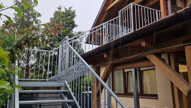 A wooden building with a metal staircase leading to a balcony.