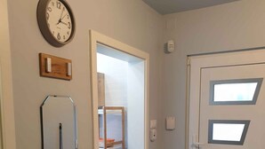 A hallway with a door, a mirror, and a clock on the wall.