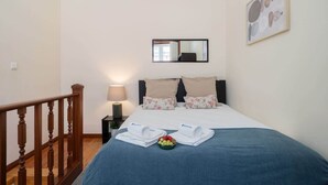 Et hotelværelse med en seng, et natbord, en lampe, et spejl og et billede i ramme på væggen.