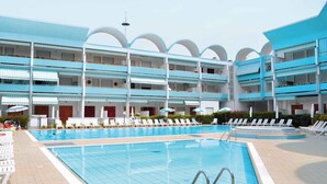 Un hôtel doté d’une grande piscine, de nombreux balcons et de chaises longues.