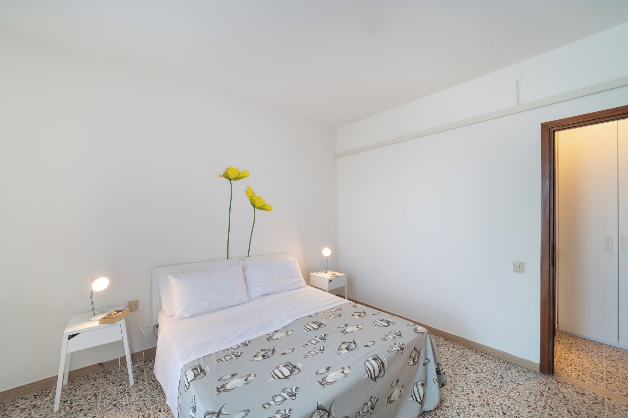 Un dormitorio con una cama, dos mesitas de noche y una puerta.