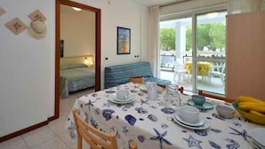 Quarto com mesa de jantar posta para dois, uma cama, um sofá e uma grande janela com vista para o exterior.