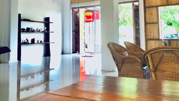 A spacious interior with a wooden ceiling, a polished floor, wicker furniture, and a visible entrance to another area. - Stay Kultura (Banda Aceh)