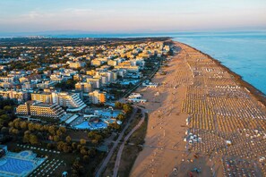 Luchtbeeld van een kuststad met een groot strand en dichte bebouwing.
