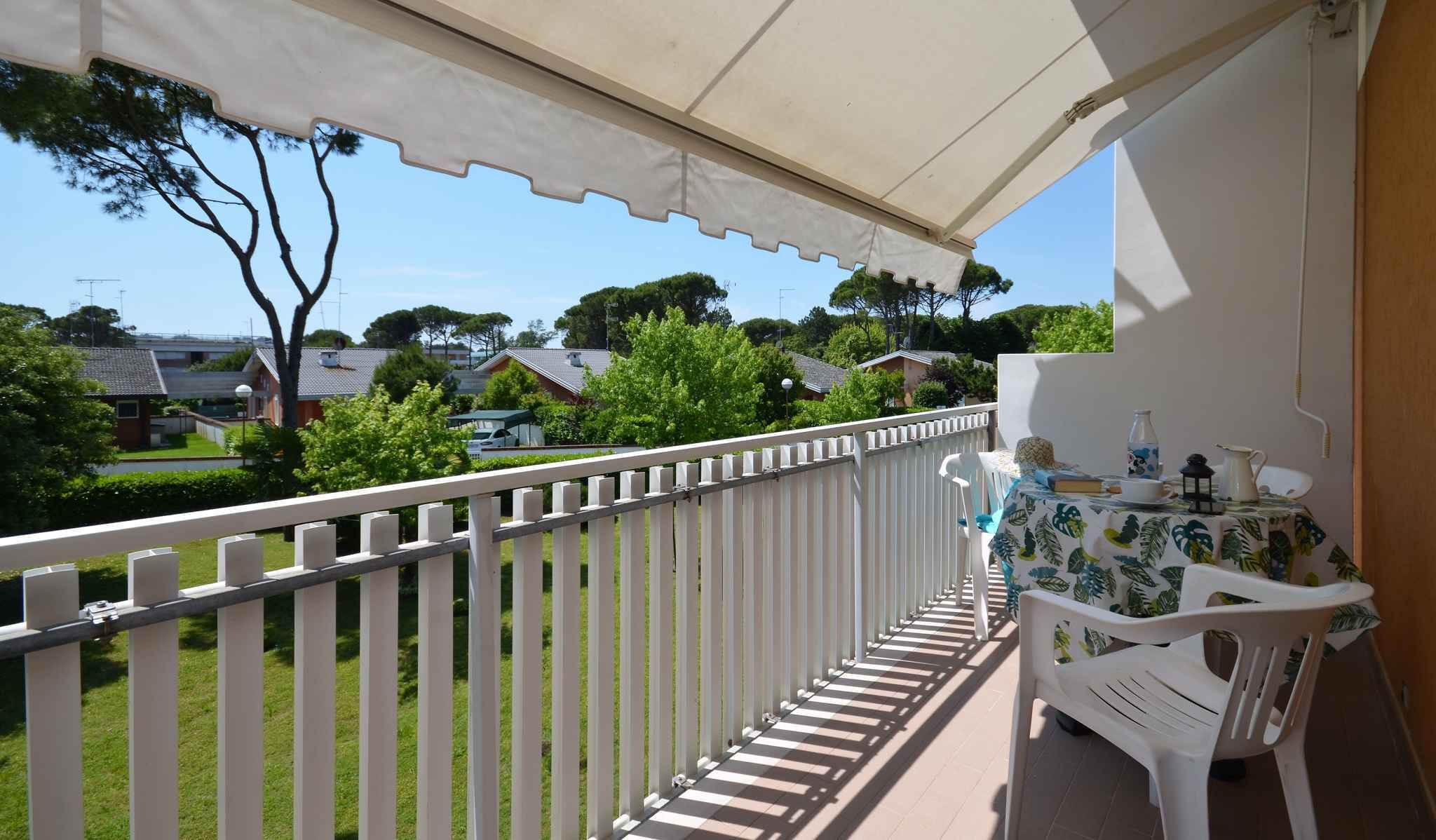 A balcony with a white railing, a table with a tablecloth, and a chair.