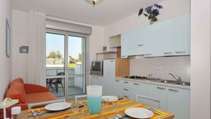 Een compact woongedeelte met een eethoek, kitchenette en een schuifdeur naar een terras.