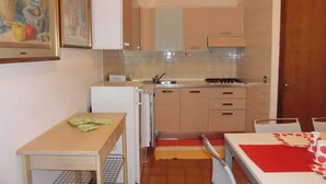 A compact kitchen with a refrigerator, stove, and cabinets.