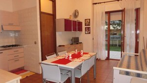 A compact kitchen with a dining table set for four, a sofa, and a small TV.
