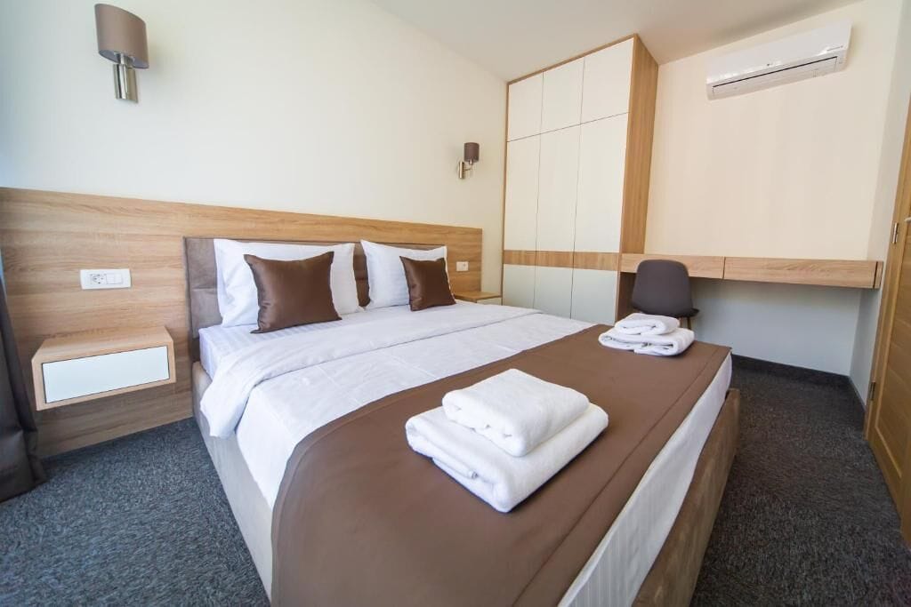 A hotel room with a large bed, a bedside table, a chair, and a wardrobe.