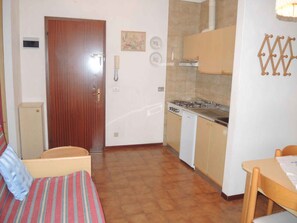 A compact kitchen with a stove, a sink, and a wooden door.