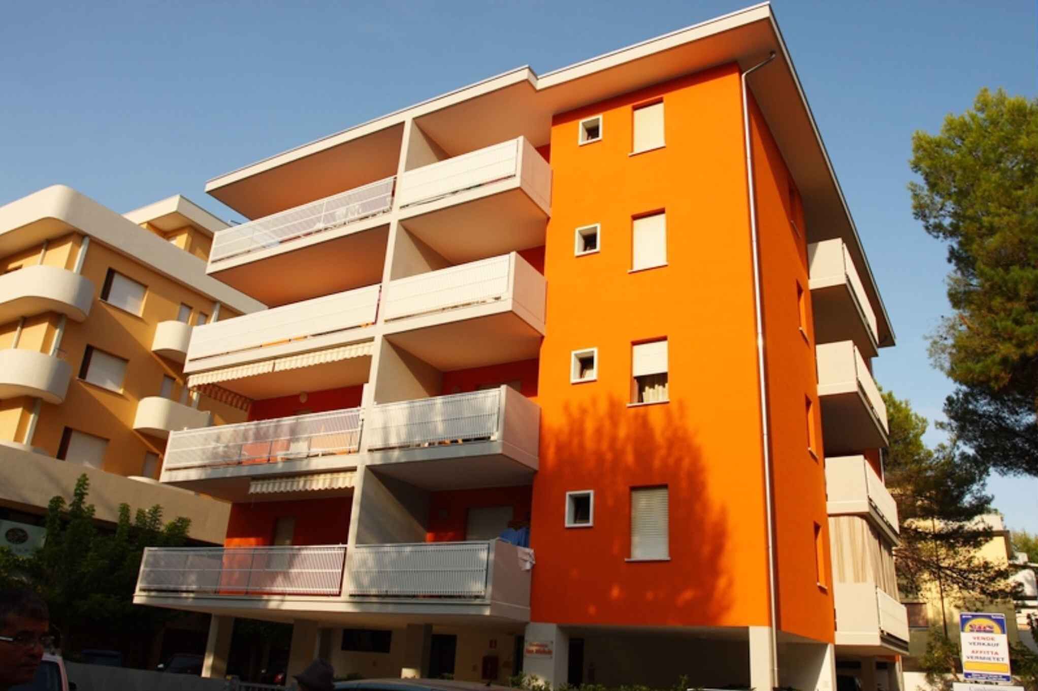 A multi-story building with balconies, a flat roof, and a clear sky.