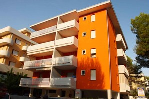 A multi-story building with balconies, a flat roof, and a clear sky.